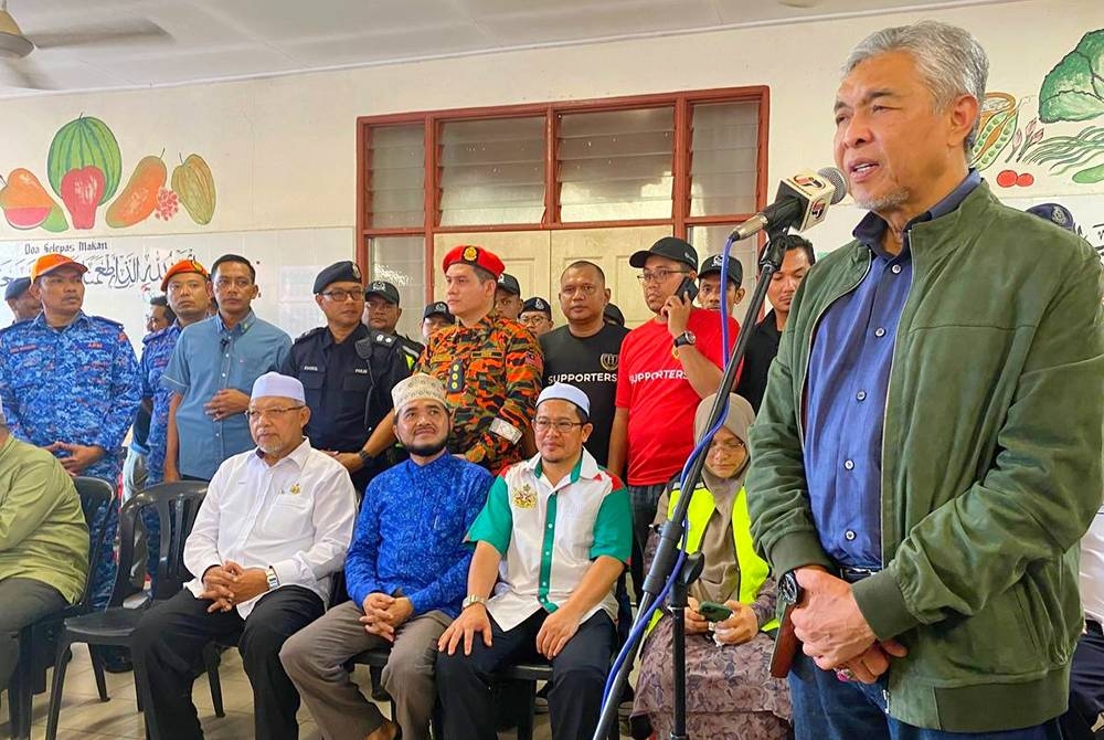 Ahmad Zahid (kanan) menyampaikan ucapan kepada mangsa banjir di PPS SK Jelor, Pasir Puteh pada Khamis.