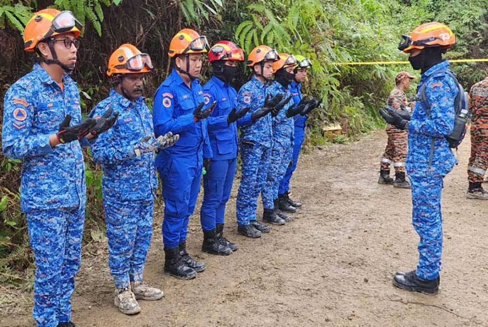 Kalaimaran (dua dari kiri) ketika bertugas di lokasi tanah runtuh di Batang Kali, Selangor.