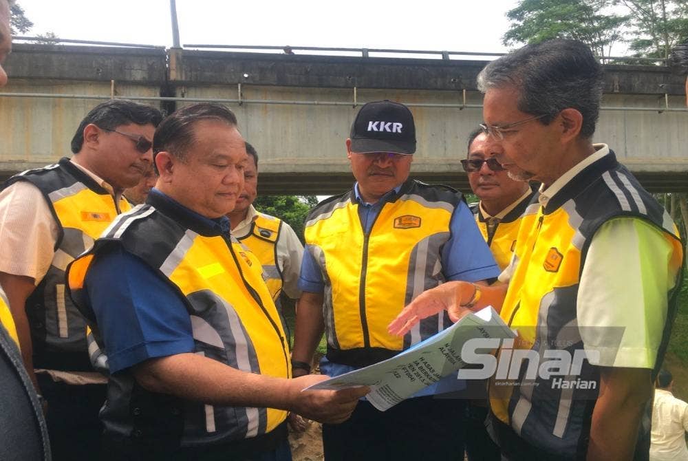 Nanta (kiri) meneliti peta lokasi cerun runtuh di bawah Jambatan Kusial, Tanah Merah, pada Jumaat.