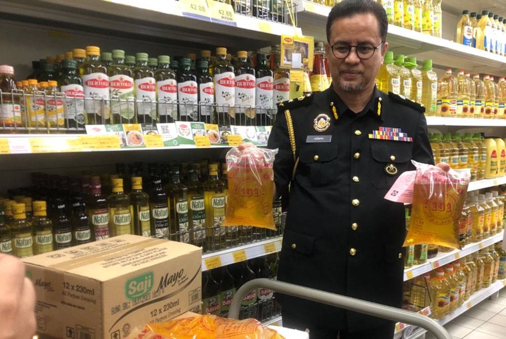 Azman menunjukkan bekalan minyak masak yang dipastikan ada di pasaran di Kelantan.