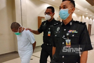 Tertuduh diiringi anggota polis keluar dari kamar mahkamah selepas selesai sebutan kesnya pada Jumaat.