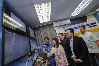 Nie Ching (dua dari kiri) mendengar penerangan daripada Pengarah Pertahanan Awam Negeri Johor, Penolong Pesuruhjaya (PA) Kamal Mokhtar (kiri) ketika melawat Pusat Kawalan Operasi Bencana di pejabat APM hari ini. - Foto Bernama