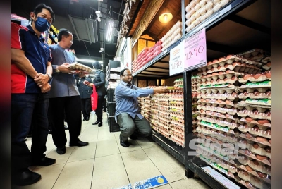Veerapan (duduk) melihat telur ayam yang dijual di sebuah pasar raya di Rembau.