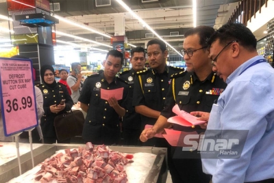 Azman (dua, kanan) melihat daging kambing biri-biri bertulang import yang dijual di Pasaraya Mydin, Tunjong, Kota Bharu.