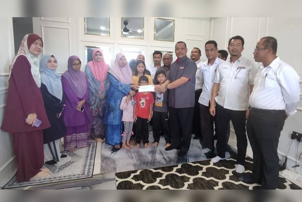 Aimi (empat dari kanan) menyerahkan faedah persaraan (kematian) kepada isteri arwah Amirul Fariz, Faziha Hamid di Yan pada petang Jumaat.