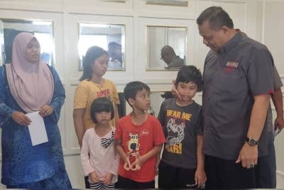 Aimi (kanan) menyantuni anak-anak arwah Amirul Fariz di Yan pada petang Jumaat.