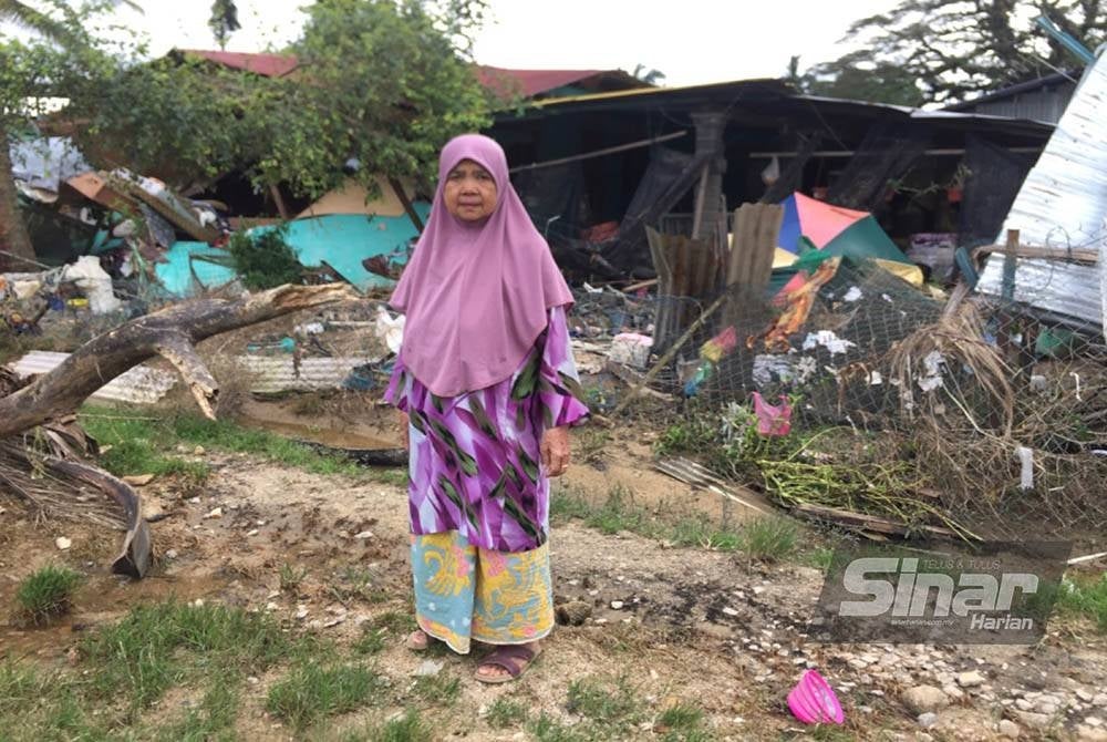 Siti Ariah sayu berdiri di hadapan rumahnya yang musnah akibat banjir.