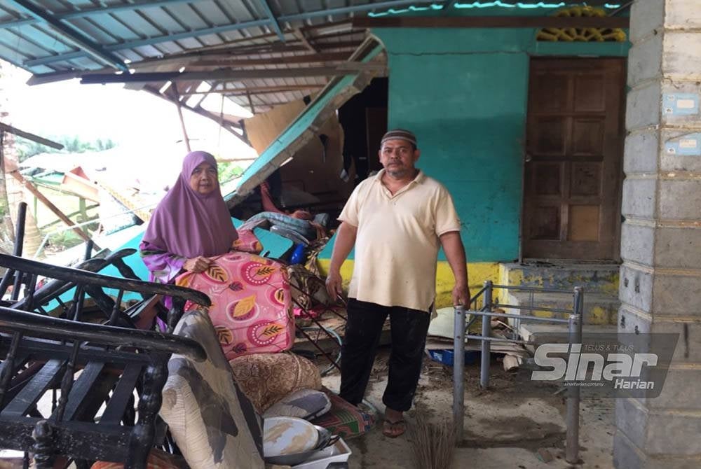 Siti Ariah dan Mohd Asri melihat barangan rumah yang rosak ditenggelami air banjir di Kuala Krai.