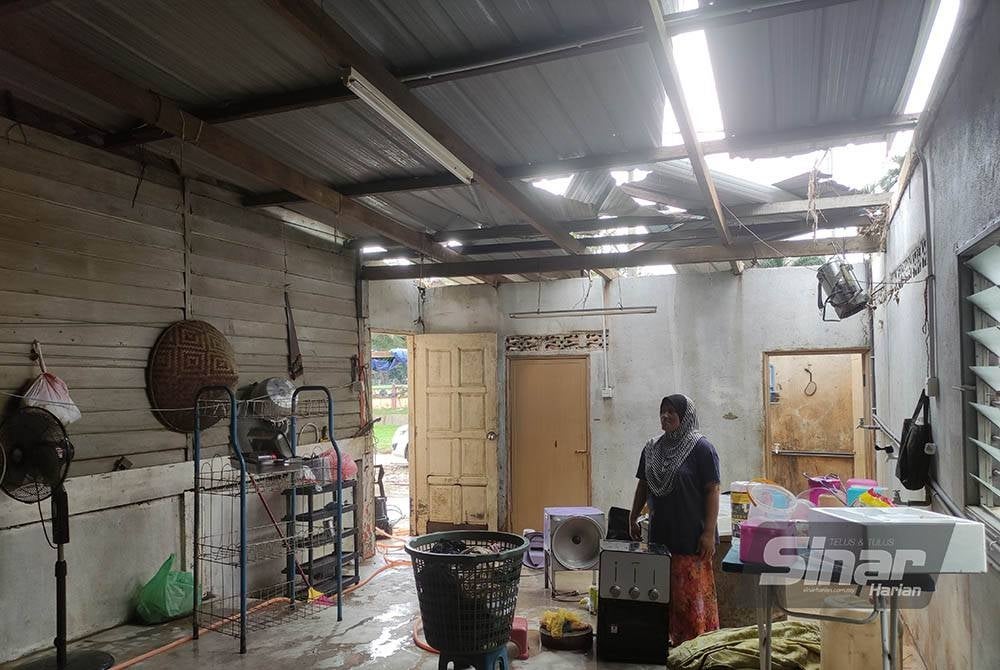 Sulaini menunjukkan sebahagian bumbung dapur rumahnya yang hilang dihanyutkan arus deras banjir.