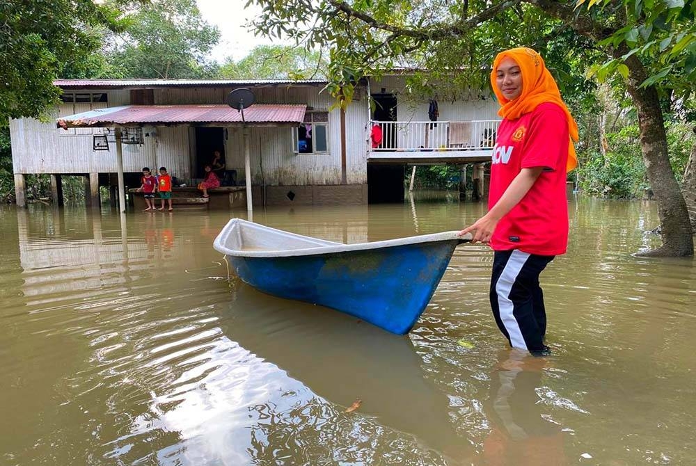 Nurul Adriana dan keluarga terpaksa menggunakan perahu untuk keluar dari kawasan rumah mereka yang masih ditenggelami air di Kampung Banggol Kong, Pasir Mas.