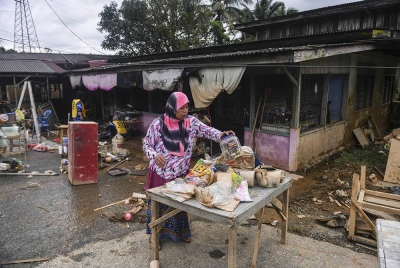 Fatimah Yassin, 61, membersihkan rumahnya susulan kejadian banjir baru-baru ini di Kampung Paya Besar pada Ahad. - Foto Bernama
