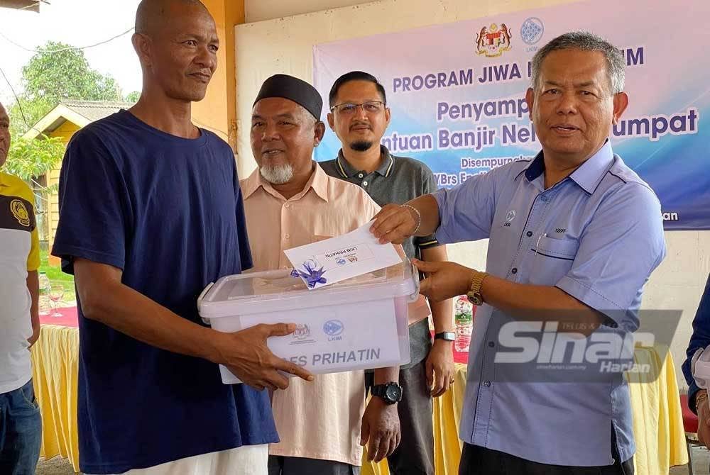 Yusoff (kanan) menyampaikan bantuan banjir kepada KIR nelayan semasa Program Jiwa Murni di Kompleks LKIM Geting, Tumpat pada Isnin.