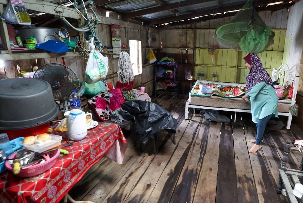 Zauyah yang merupakan OKU fizikal membersihkan rumahnya yang ditenggelami banjir baru-baru ini di Kampung Ana pada Isnin. - foto: Bernama