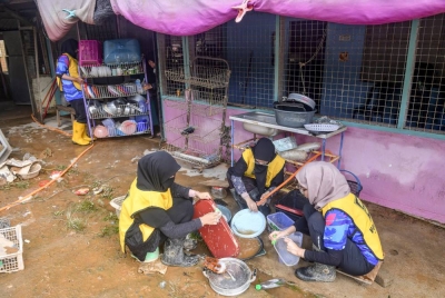 Beberapa sukarelawan berkerjasama membersihkan rumah mangsa banjir ketika tinjauan di Kampung Paya Besar pada Ahad. - Foto Bernama