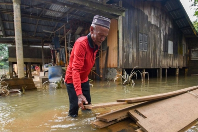 Che Ali memeriksa papan akan digunakan untuk membaiki rumahnya yang turut tenggelam susulan kejadian banjir baru-baru ini ketika tinjauan Kampung Tersang, Rantau Panjang pada Isnin. - Foto Bernama