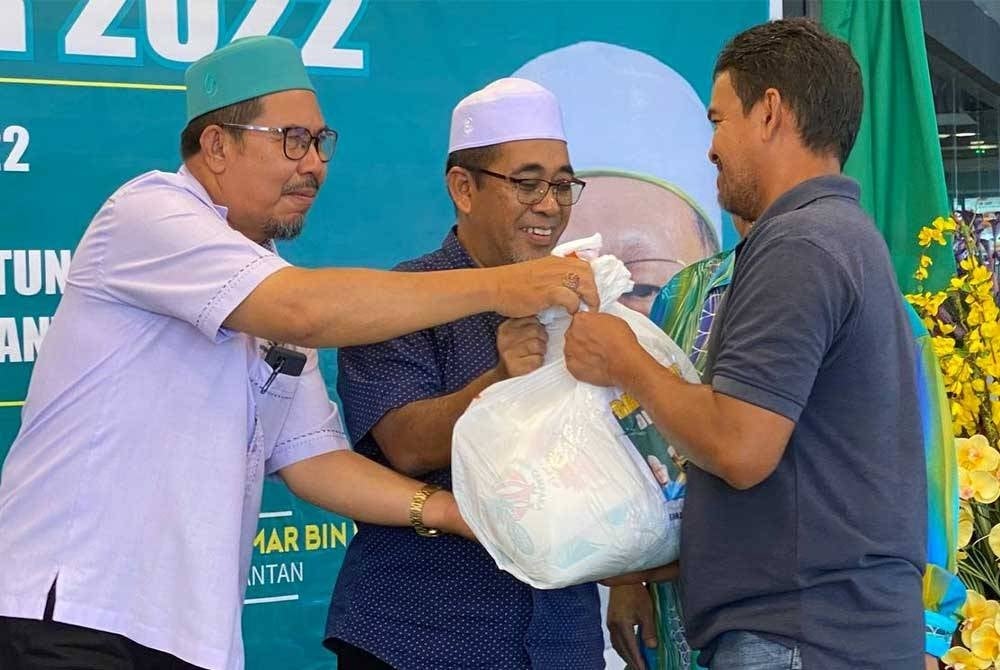 Abd Rahman (tengah) menyampaikan sumbangan kepada mangsa banjir ketika Program Bantuan Banjir anjuran Pasar Raya G-Orange di Tunjong, Kota Bharu pada Selasa.