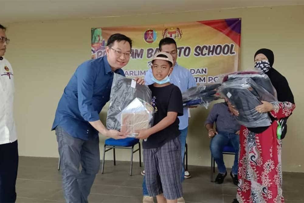 Wee Tse (dua dari kiri) menyampaikan sumbangan kepada seorang penerima selepas Program Back To School di Kampung Kopok Baru, Pasir Gudang pada Selasa.