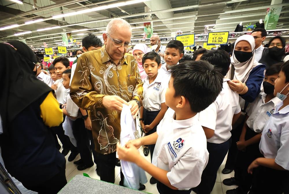 Ahimmat membantu penerima mencuba baju sekolah.