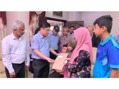 John Riba (dua dari kiri) menyerahkan bantuan Perkeso kepada Salina sambil disaksikan anak-anaknya di rumah mereka di Kota Warisan pada Khamis.