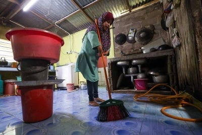 Zauyah Deraman, 36, yang merupakan orang kurang upaya fizikal membersihkan rumahnya yang ditenggelami banjir, baru-baru ini di Kampung Ana, Tumpat, Kelantan. - Foto Bernama