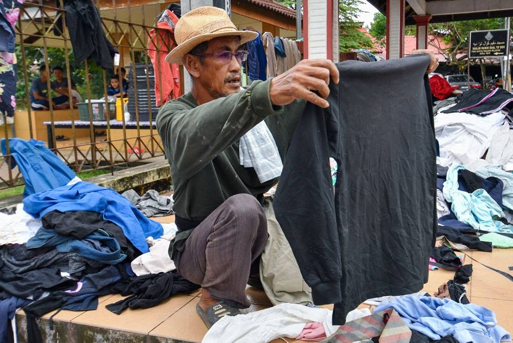 Penduduk kampung memilih pakaian terpakai yang disumbangkan untuk mangsa-mangsa banjir di PPS Sekolah Kebangsaan Gual To'Deh, Rantau Panjang. - Foto Bernama.