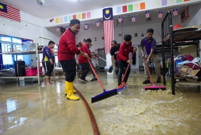 Anggota Pasukan Bomba Sukarelawan dan Badan Bukan Kerajaan membantu membersihkan asrama pelajar Madrasah Darul Bayan, Pondok Pinang Merah Paka, Dungun selepas banjir mulai surut di kawasan tersebut pada Sabtu. - Foto Bernama