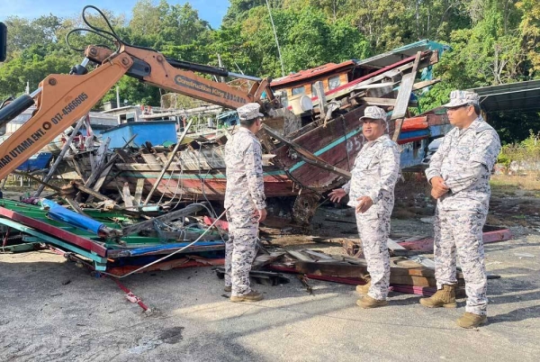 Abd Razak (tengah) bersama pegawainya ketika memantau proses pelupusan bot nelayan asing yang dilucut hak.