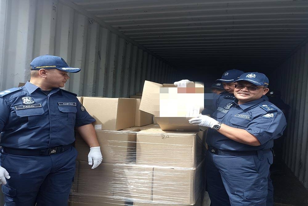 Misbahudin (kanan) menunjukkan rokok seludup yang dirampas di Pelabuhan Pasir Gudang pada 9 Disember lalu.