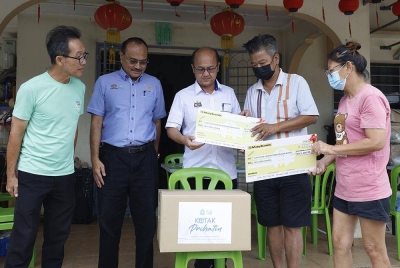 Hee Sem (tengah) menyerahkan replika cek tuntutan faedah pengurusan mayat kepada Hua Keong (dua dari kanan) dan isteri, Chia Eet Loun, 51, (kanan) ketika program Skuad Prihatin Perkeso Melaka di kediaman mereka di Kampung Permai dekat Machap Umboo pada Khamis. - Foto Bernama