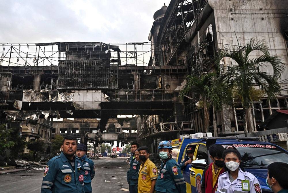 Des secouristes thaïlandais se tiennent devant une partie d'un hôtel-casino détruit après un incendie à Poipet vendredi.  -Photo AFP