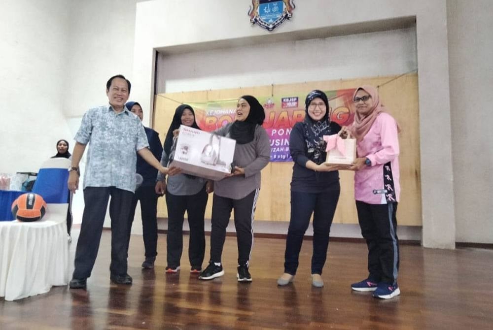 Ahmad (kiri) menyampaikan hadiah kepada pasukan bola jaring di Dewan Muafakat Taman Saujana pada Sabtu.