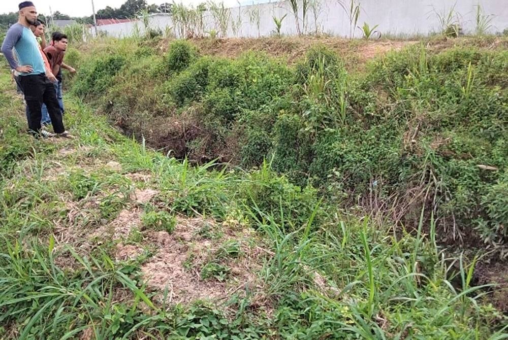 Penduduk melihat parit di hadapan perumahan mereka yang mudah melimpah jika hujan berterusan.