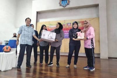 Ahmad (kiri) menyampaikan hadiah kepada pasukan bola jaring di Dewan Muafakat Taman Saujana pada Sabtu.