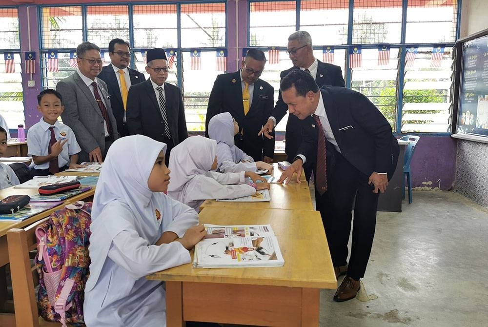 Abdul Muie (kanan) berbual bersama murid di SK Pulau Rusa pada hari pertama sesi persekolahan penggal ketiga di sekolah berkenaan pada Ahad.