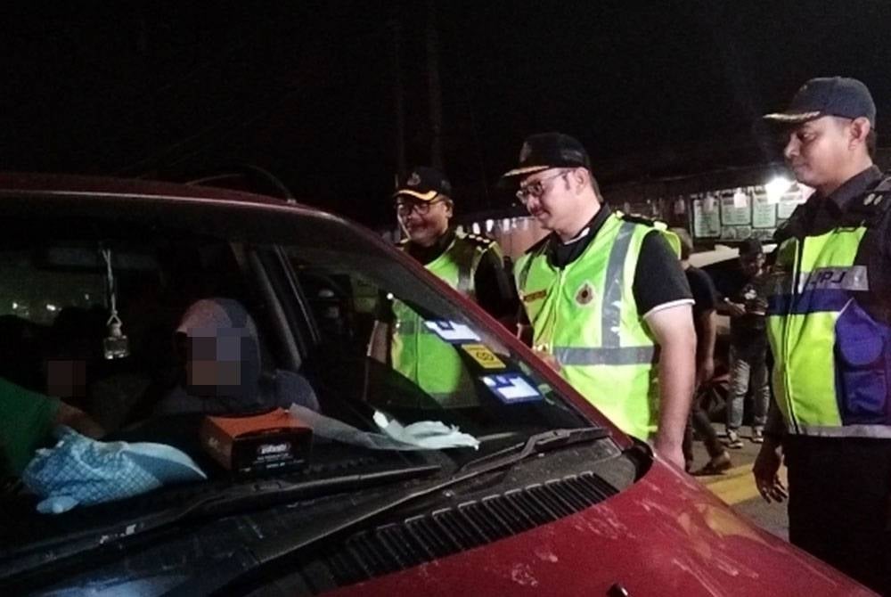 Mohd Misuari (tengah) memeriksa lesen pemandu dalam Ops Khas Ambang Tahun Baru 2023 Jabatan Pengangkutan Jalan Kelantan di Jalan Pasir Hor, pada Sabtu.
