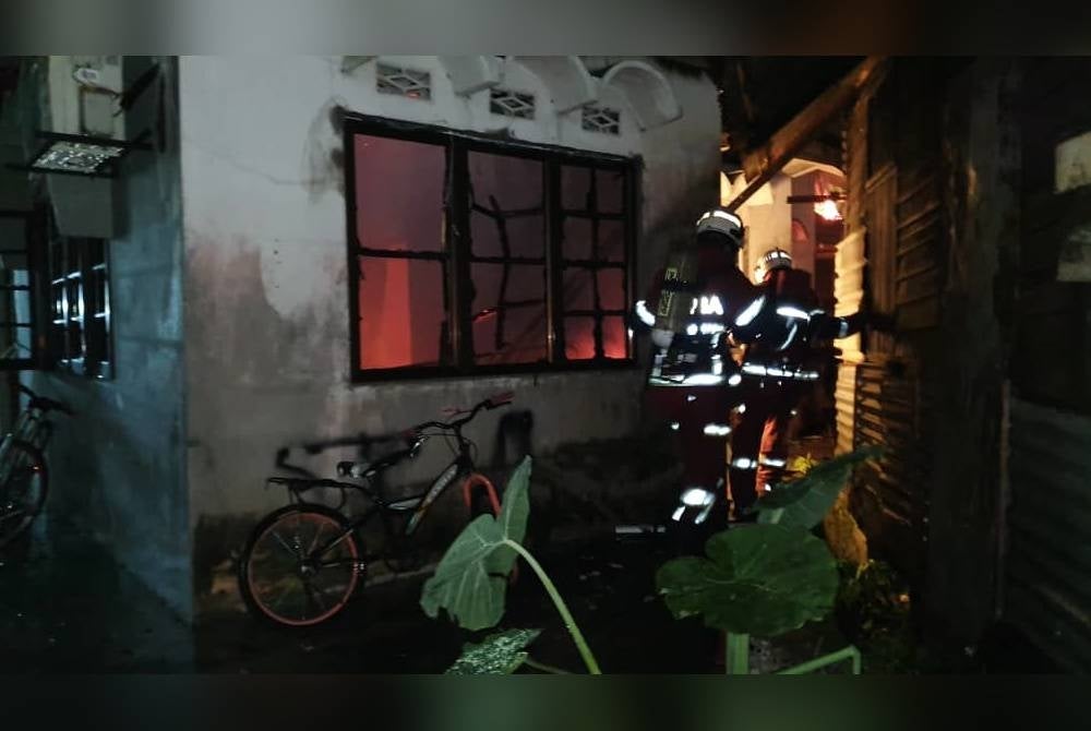 Anggota bomba sedang memadamkan kebakaran melibatkan sebuah rumah di Jalan Dewan Simpang Tiga pada Isnin.