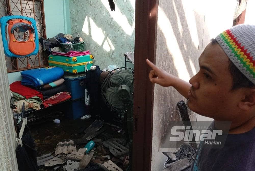 Muhammad Tarmizi menunjukkan keadaan rumahnya yang terbakar dalam kejadian di Jalan Dewan Simpang Tiga, Gombak Selangor pada Isnin.