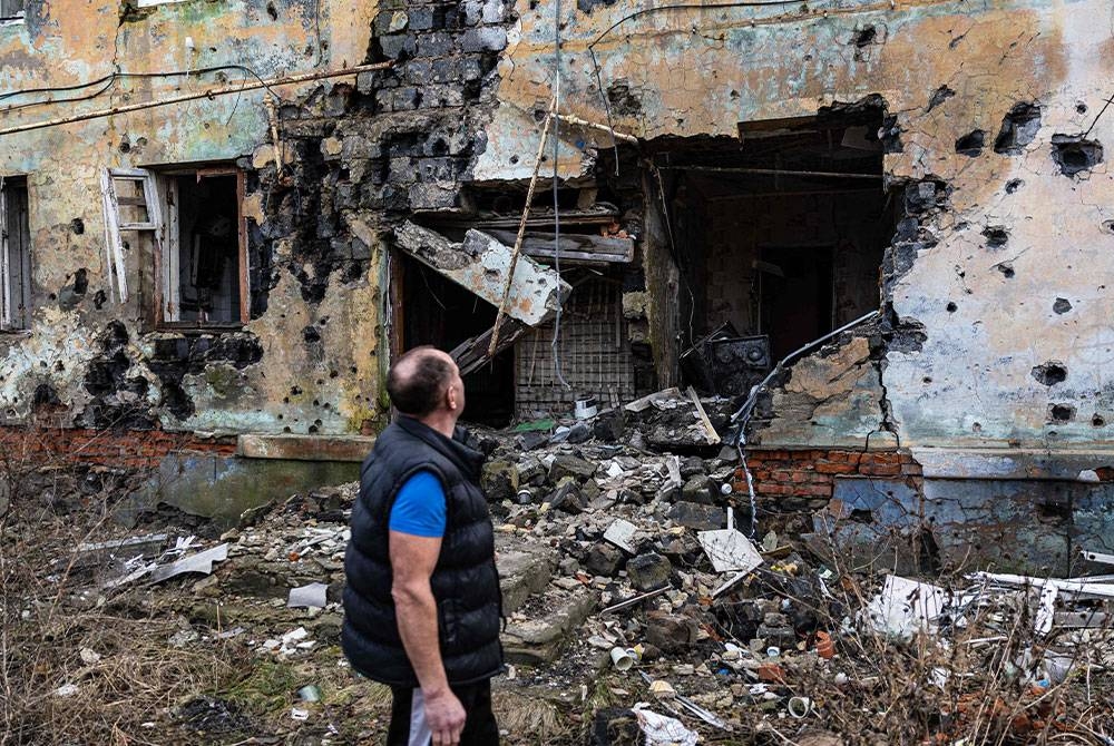 Andryi Pleshan, 60 tahun, memeriksa kemusnahan di sekitar tempat perlindungannya di bandar Izium, timur Ukraine pada 2 Januari 2023. - Foto AFP