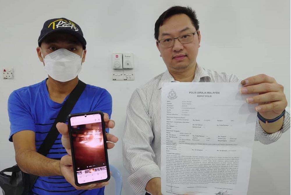 Hang Lim (kiri) dan Wee Tse menunjukkan salinan laporan polis dan foto dikhianat dengan api, selepas sidang akhbar di Pejabat Khidmat Ahli Parlimen Tebrau, di Ulu Tiram, Johor Bahru, pada Rabu.