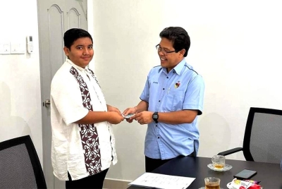 Mohamad Rafie (kanan) menghulurkan sumbangan kepada Muhammad Syakawie.