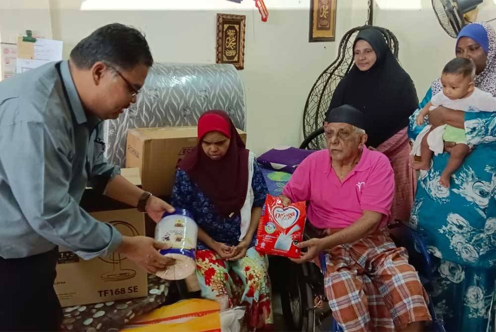 Mas Imran Adam (kiri) menyampaikan sumbangan barangan keperluan harian dan perkakas elektrik kepada Abd Hameed.