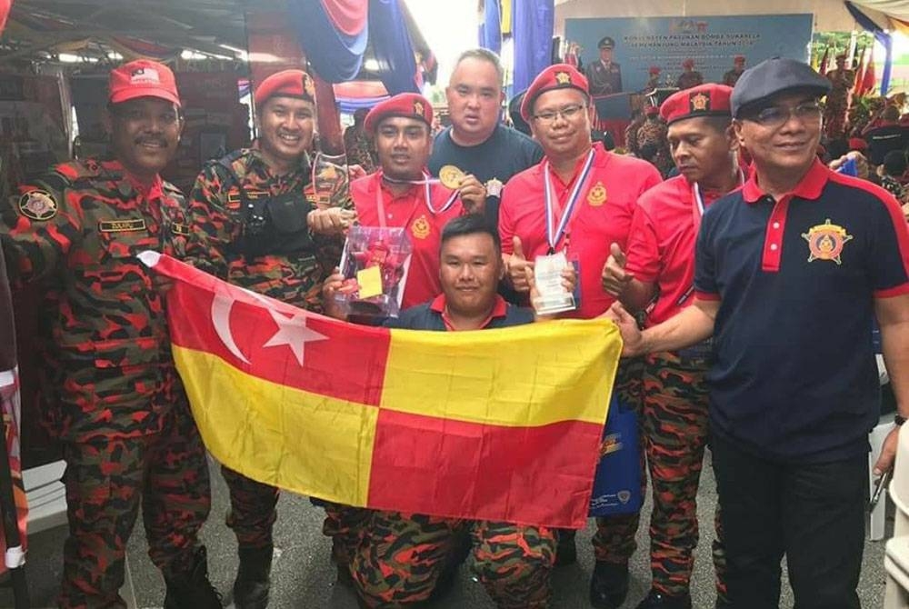 Mohammad Firdaus (tiga dari kiri) bersama anggota sukarelawan bomba menjadi johan dalam satu pertandingan ketika Konvensyen Bomba Sukarela Semenanjung pada 2018.