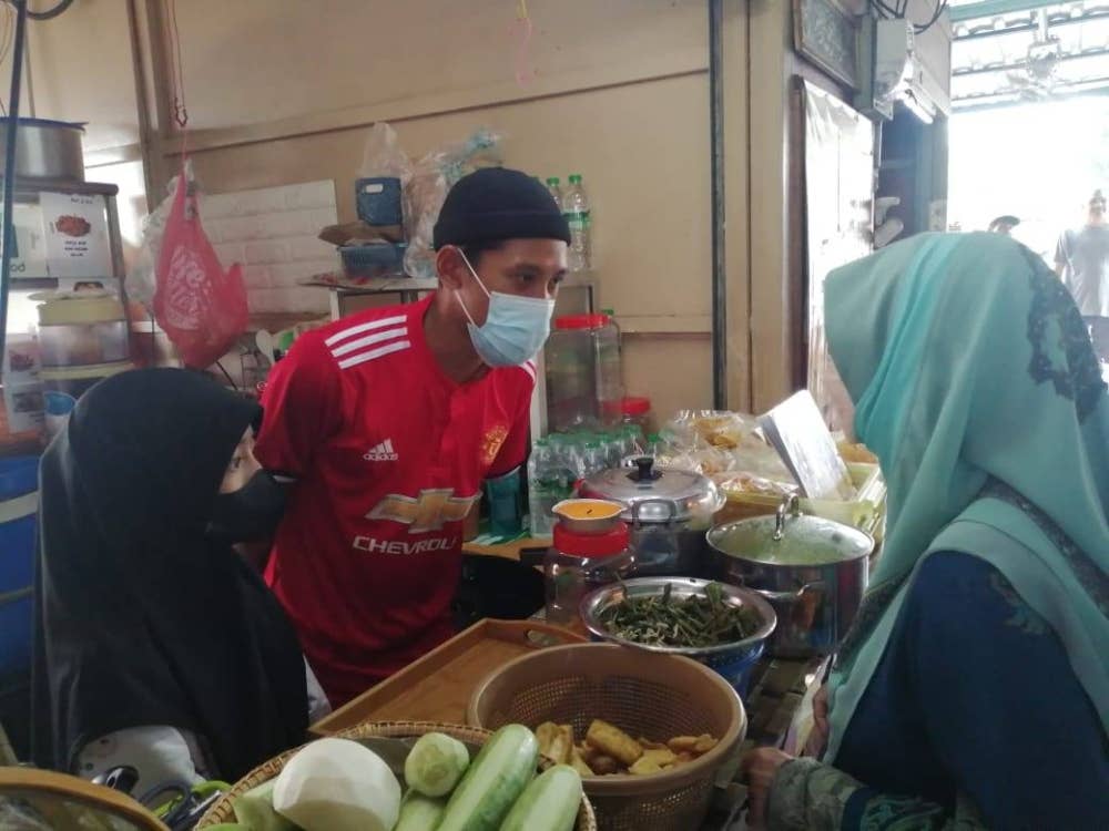 Muhammad Faizul memakai pelitup muka sewaktu meniaga makanan.