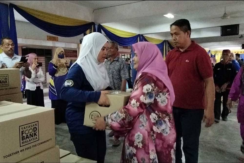 Puteri Fazlieznoor (kiri) menyampaikan kotak makanan kepada penerima terpilih.