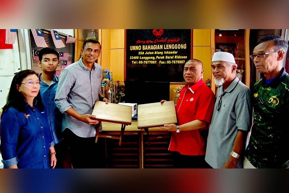 Saarani (troisième à partir de la droite) recevant un don de 600 rehals présenté par Mustafar (troisième à partir de la gauche) au bureau de l'UMNO Lenggong samedi.