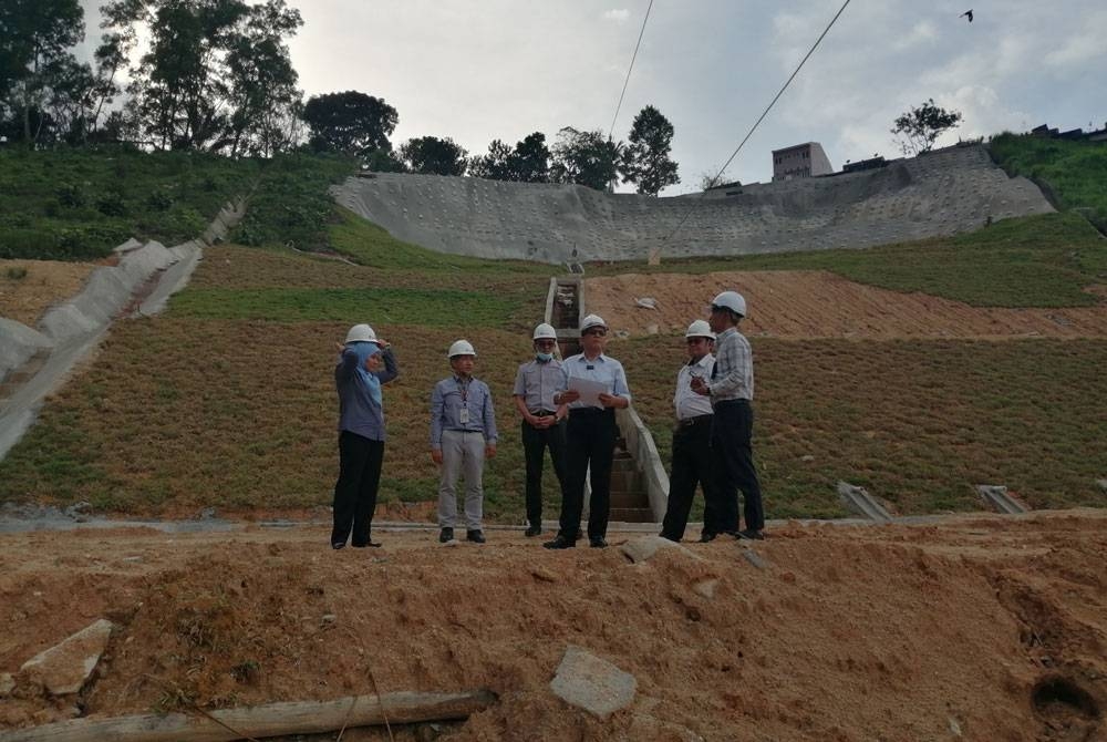 Izham (tiga dari kanan) meninjau kerja pengukuhan cerun di Taman Bukit Permai pada Isnin.
