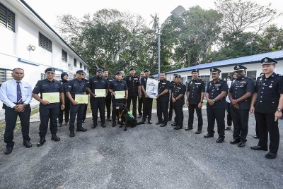 Suresh Kumar bergambar bersama para pegawainya selepas menyampaikan sijil penghargaan dan pingat kepada 'Black' dan pengendalinya, Koperal Johan Anak Jame di Seksyen K9 pada Rabu. - Foto Bernama