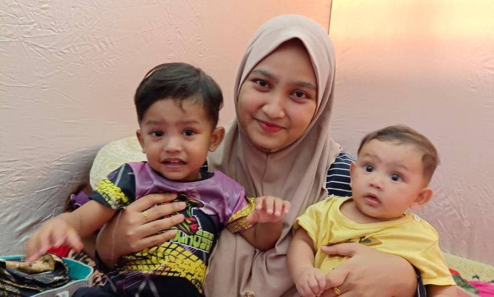 Aida Farlyssa Hezetty mendukung dua anaknya ketika mengharungi banjir di Kampung Sahom, Kampar. 