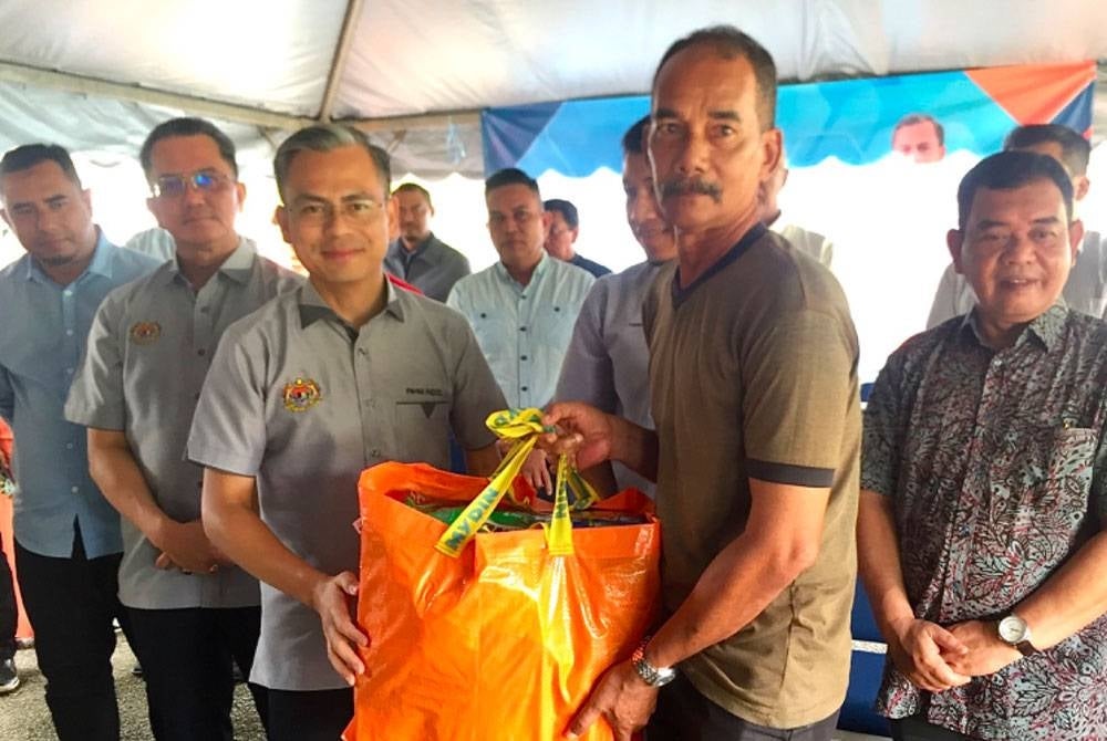 Ahmad Fahmi (tiga dari kiri) menyampaikan bantuan kepada pengawal keselamatan Kamaruzaman Yusof (dua dari kanan).