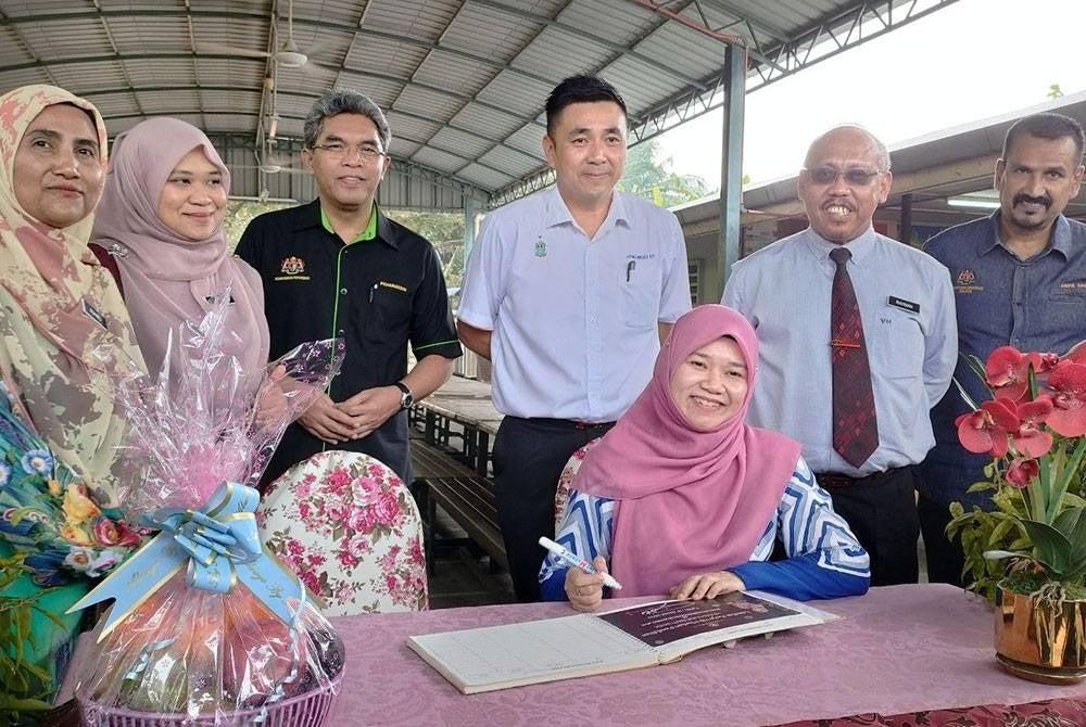 Fadhlina menurunkan tandatangan pada buku pelawat di SK Keledang Jaya, Nibong Tebal pada Jumaat.